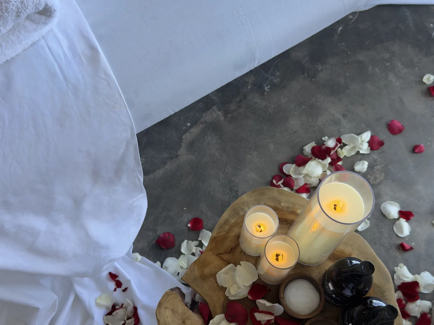 Candles, massage oils and flower petals prepared beside a spa treatment bed at VANARA